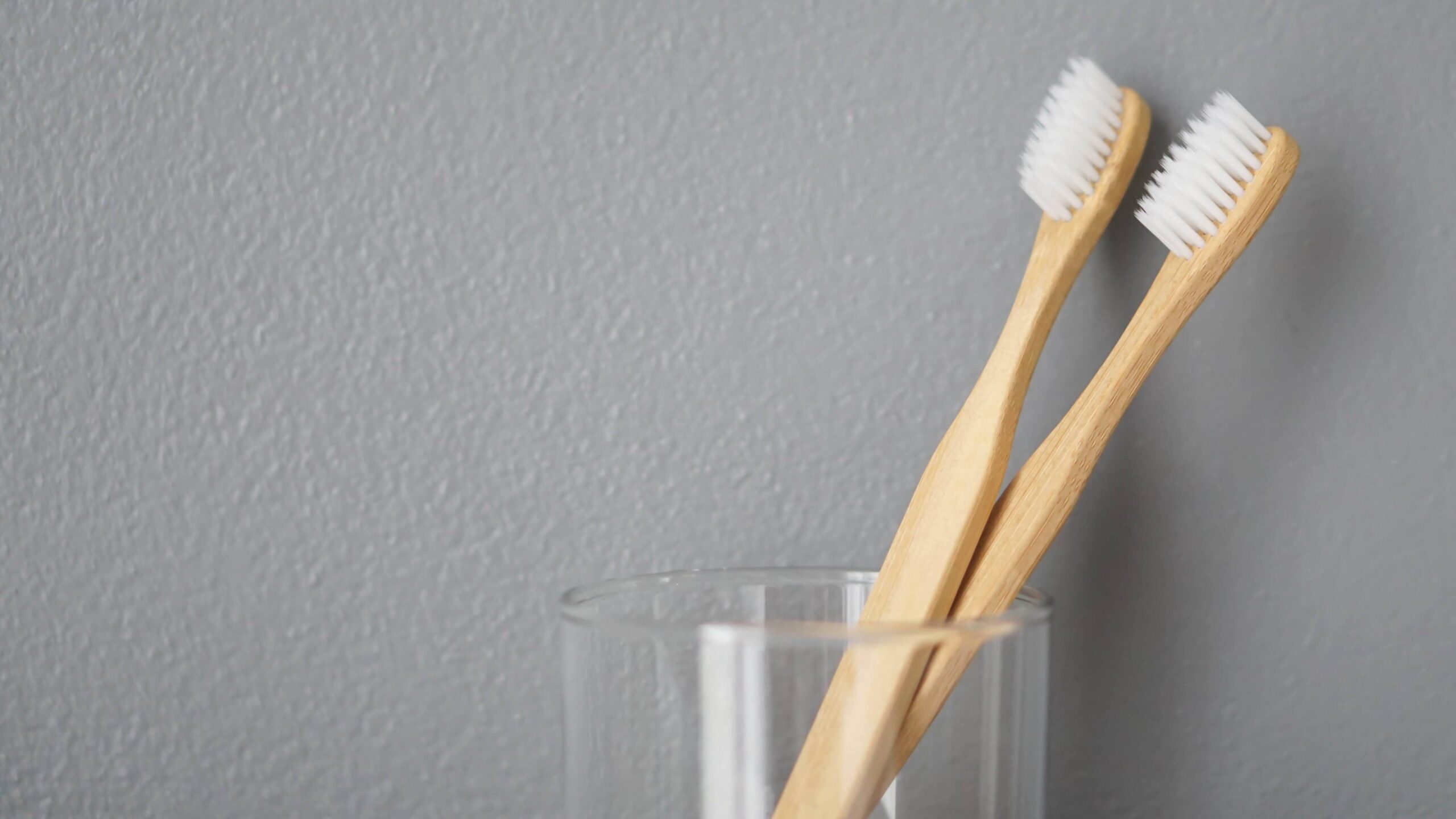 Close up wooden toothbrush in glass with grey background, selective focus